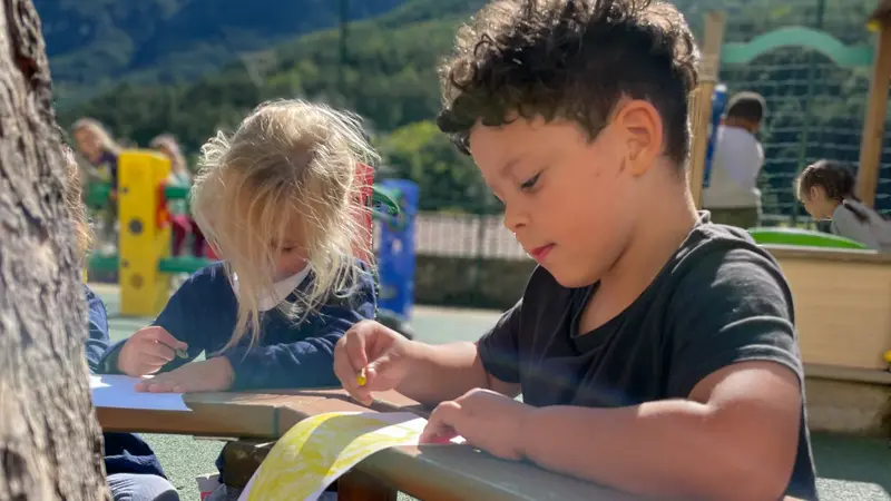 Jeunes enfants qui dessinent sur un banc dans la cour de récréation